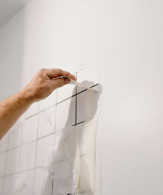 Crop anonymous male doing renovation works in room with tiled walls at home