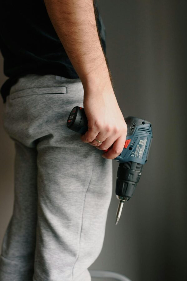 Crop man holding drill in hand